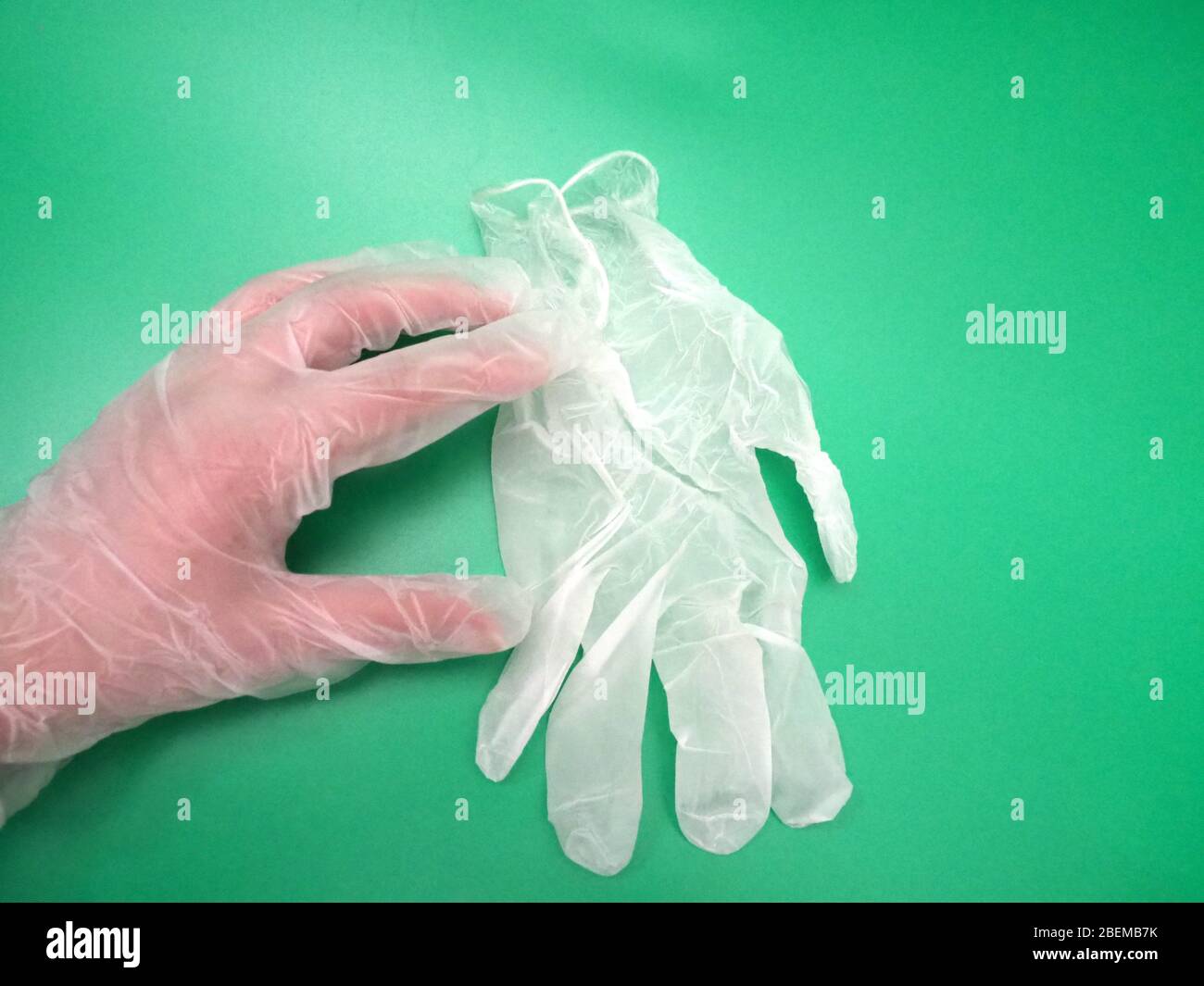 Hand Wearing A White Disposable Glove (PPE) Reaching Out And Picking Up