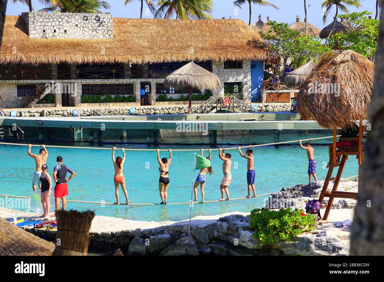 Children having fun, walking on rope in water at Xcaret Park, Riviera Maya, Mexico Stock Photo