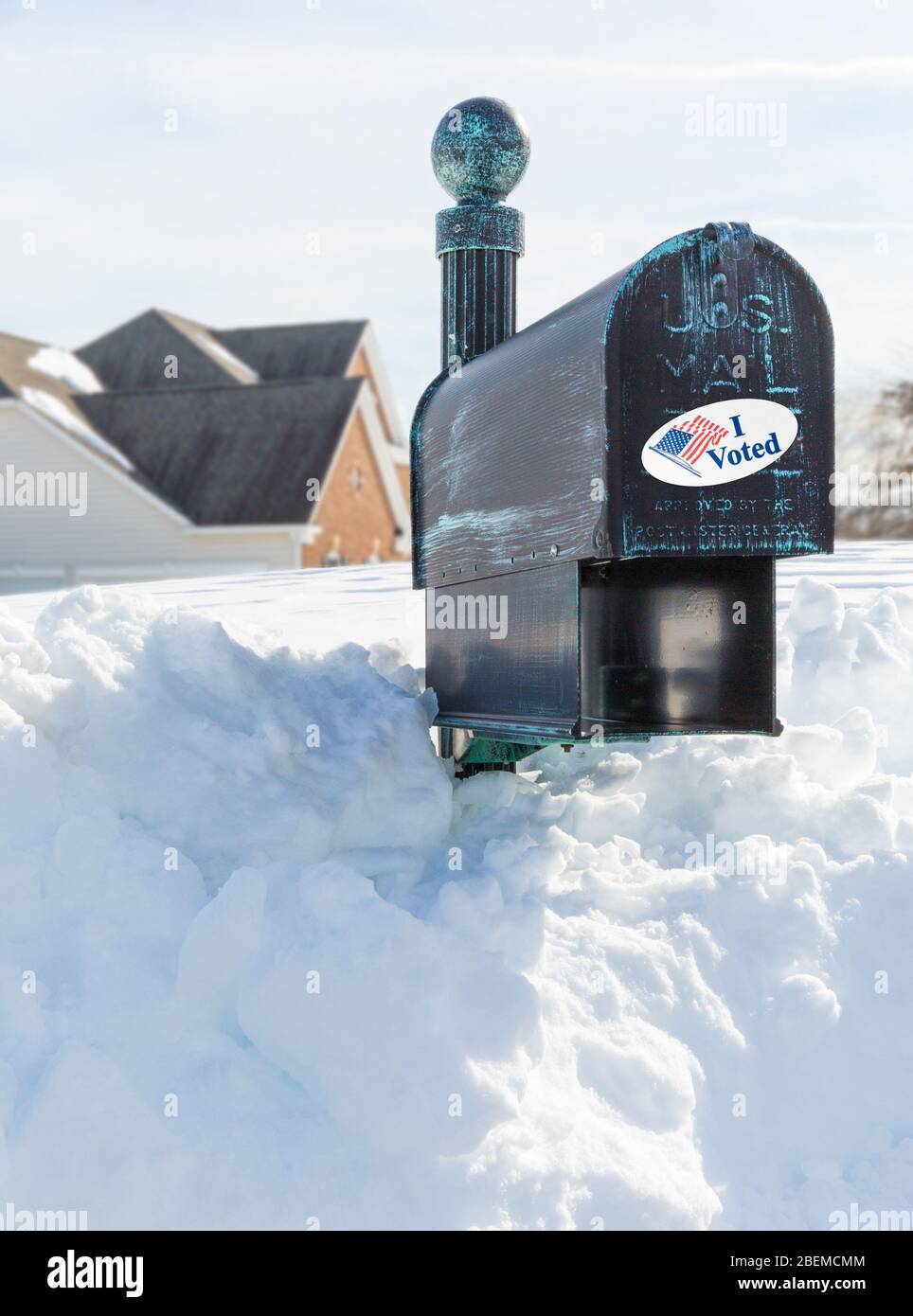 Metal mailbox for rural homes buried in deep snow with I Voted sticker as concept for voting by mail or absentee ballot paper Stock Photo