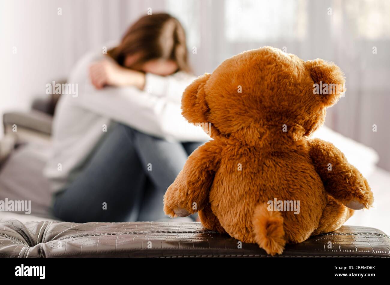 Sitting upset woman and teddy bear. Selective focus. Break up concept Stock Photo