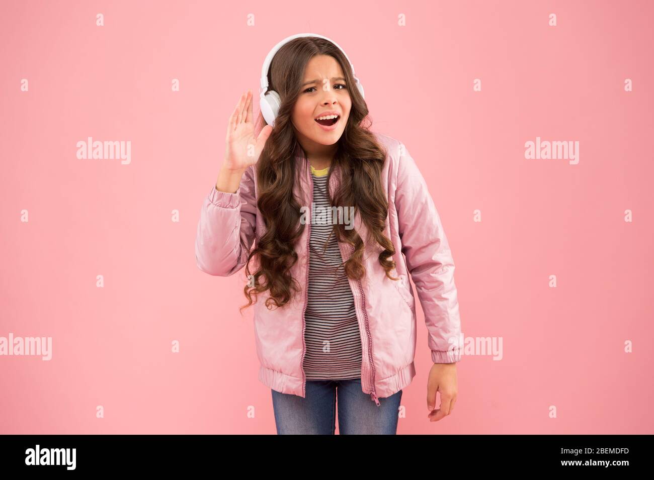 let me hear it. Music gives joy. Happy child listen to music pink background. Little girl wear headphones playing music. New technology for kids. Fun and entertainment. Modern lifestyle. Stock Photo