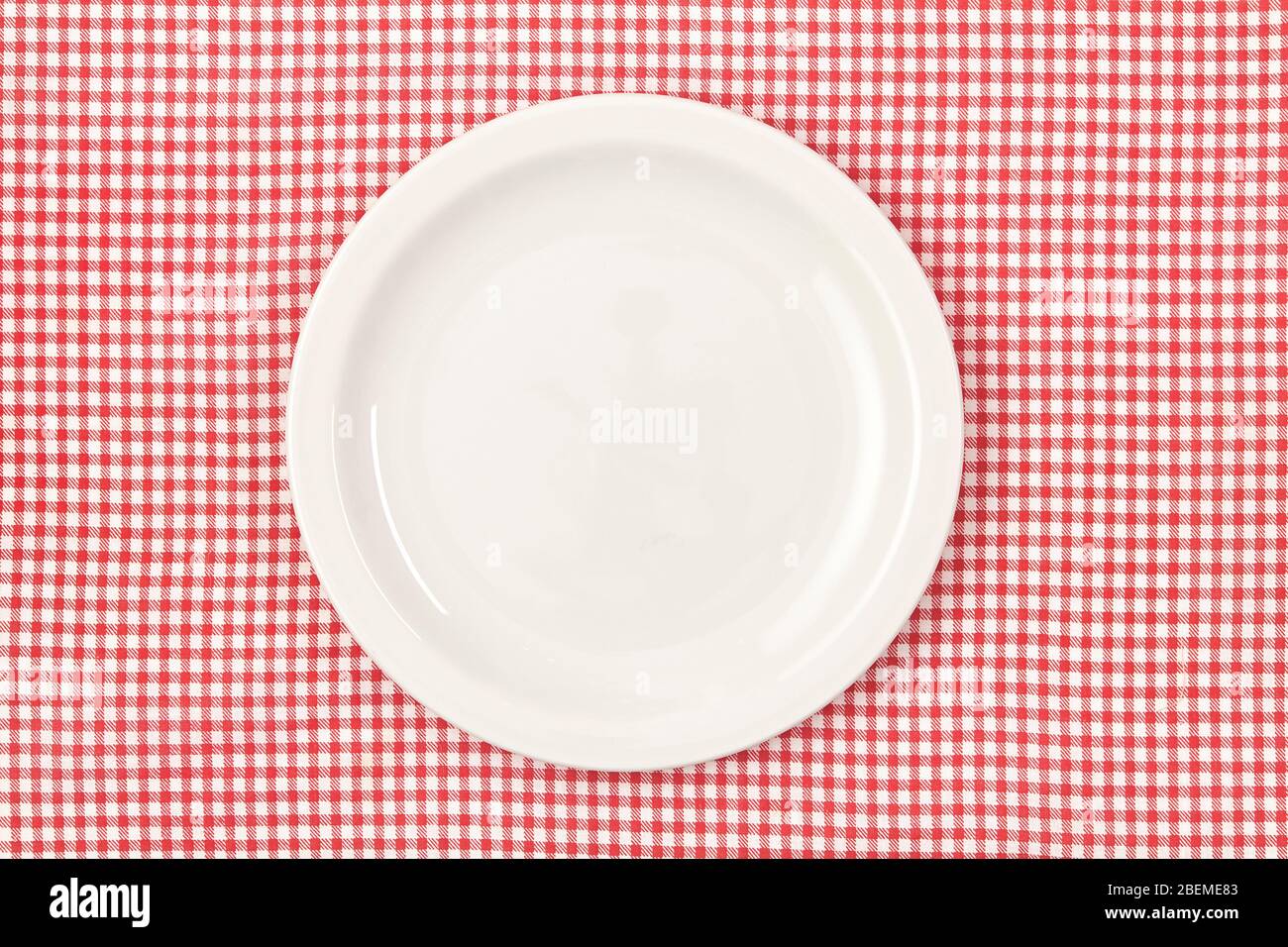 White empty plate on red checked tablecloth Stock Photo