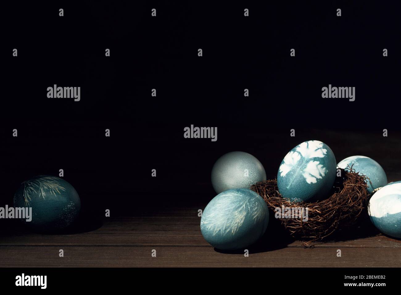 Painted blue eggs with printed picture of parsley in nest on wooden table. Easter decoration concept. Top view rustic background Stock Photo