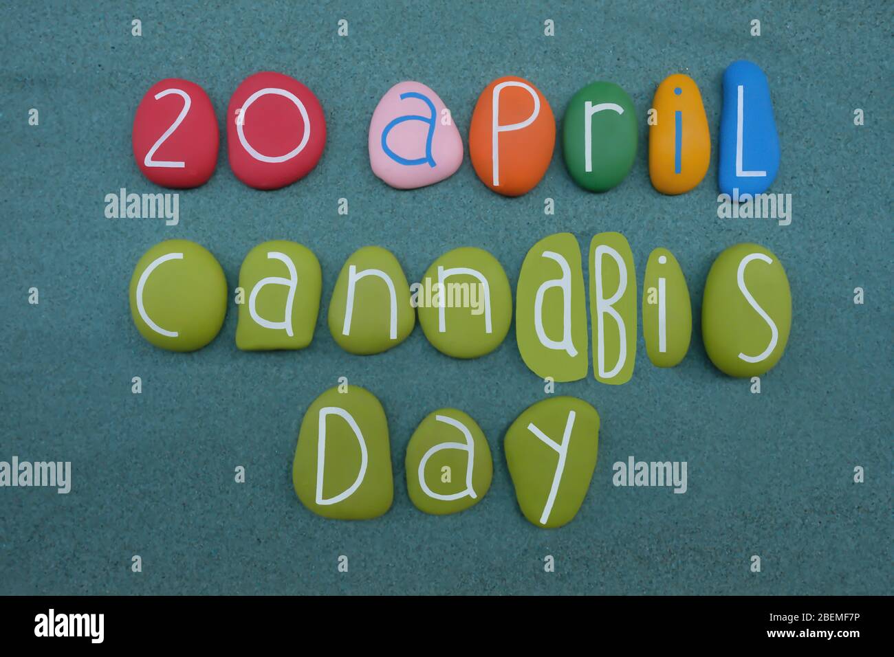 20 April, Cannabis Day celebrated with a multi colored stone letters composition over green sand Stock Photo