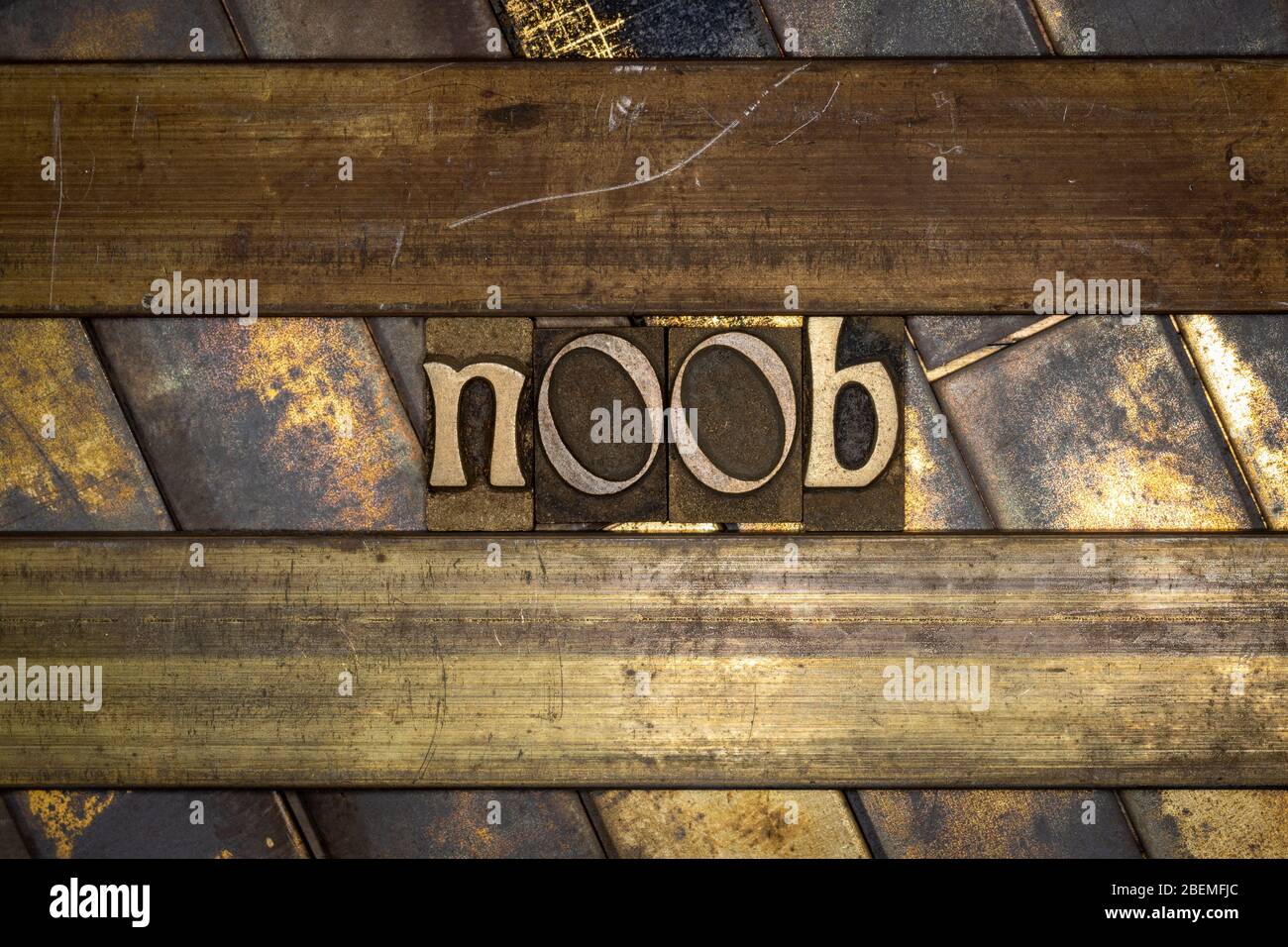 Photo of real authentic typeset letters forming noob text on vintage textured grunge copper and gold background Stock Photo