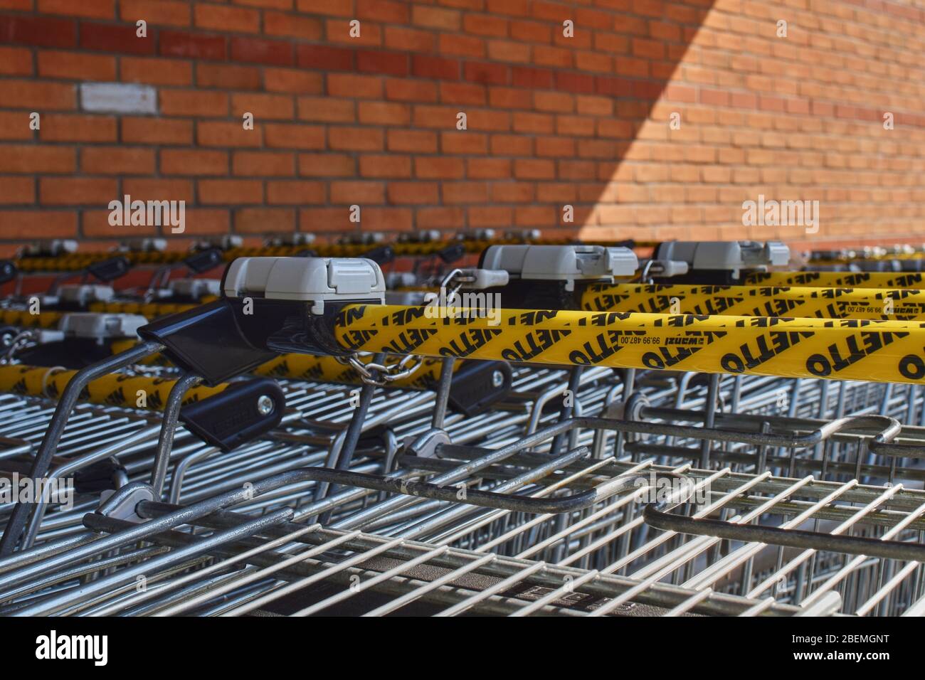 Berlin, Germany - April 02, 2018: A row of shopping trolleys with focus on the handles and locks that can be unlocked with a coin to borrow one of the Stock Photo