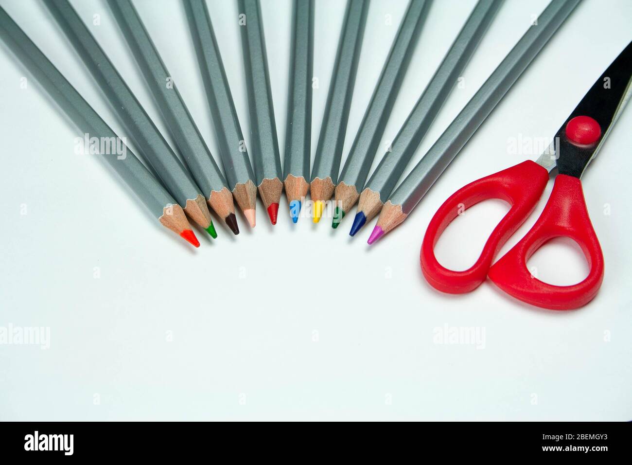 Scissors and colored pencils on a white background Stock Photo