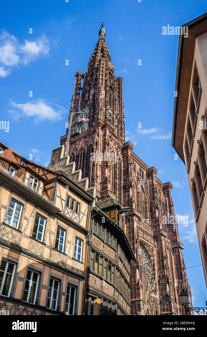 the spire of north tower of Strasbourg Cathedral rises above medieval timber-framed buildings at Place De La Cathédrale, Strasbourg, Alsace, France Stock Photo
