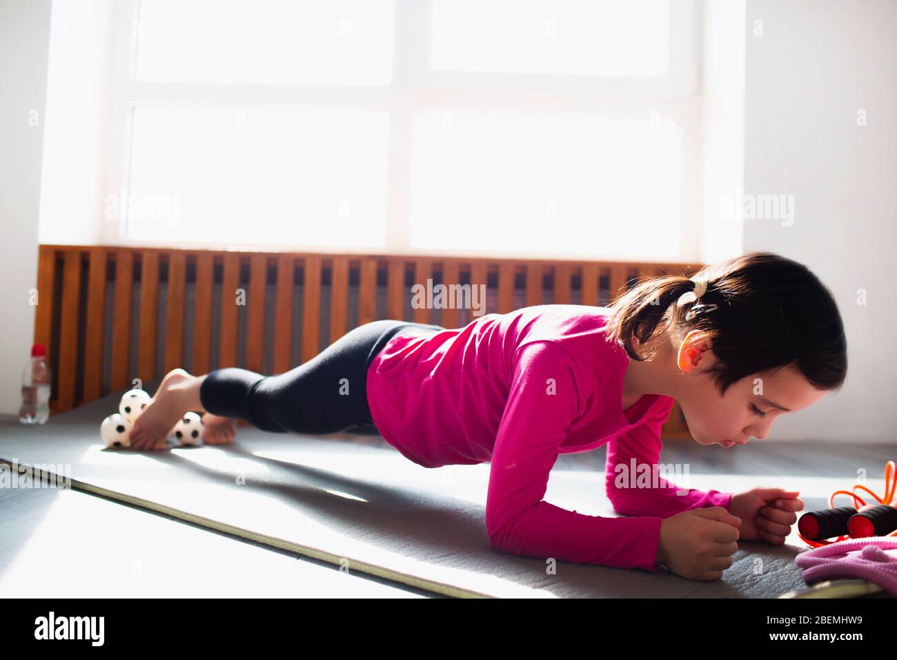 Little girl Doing a Plank Exercise workout at home. Cute kid is training on a mat indoor. Little dark haired female model in sportswear has exercises Stock Photo Alamy
