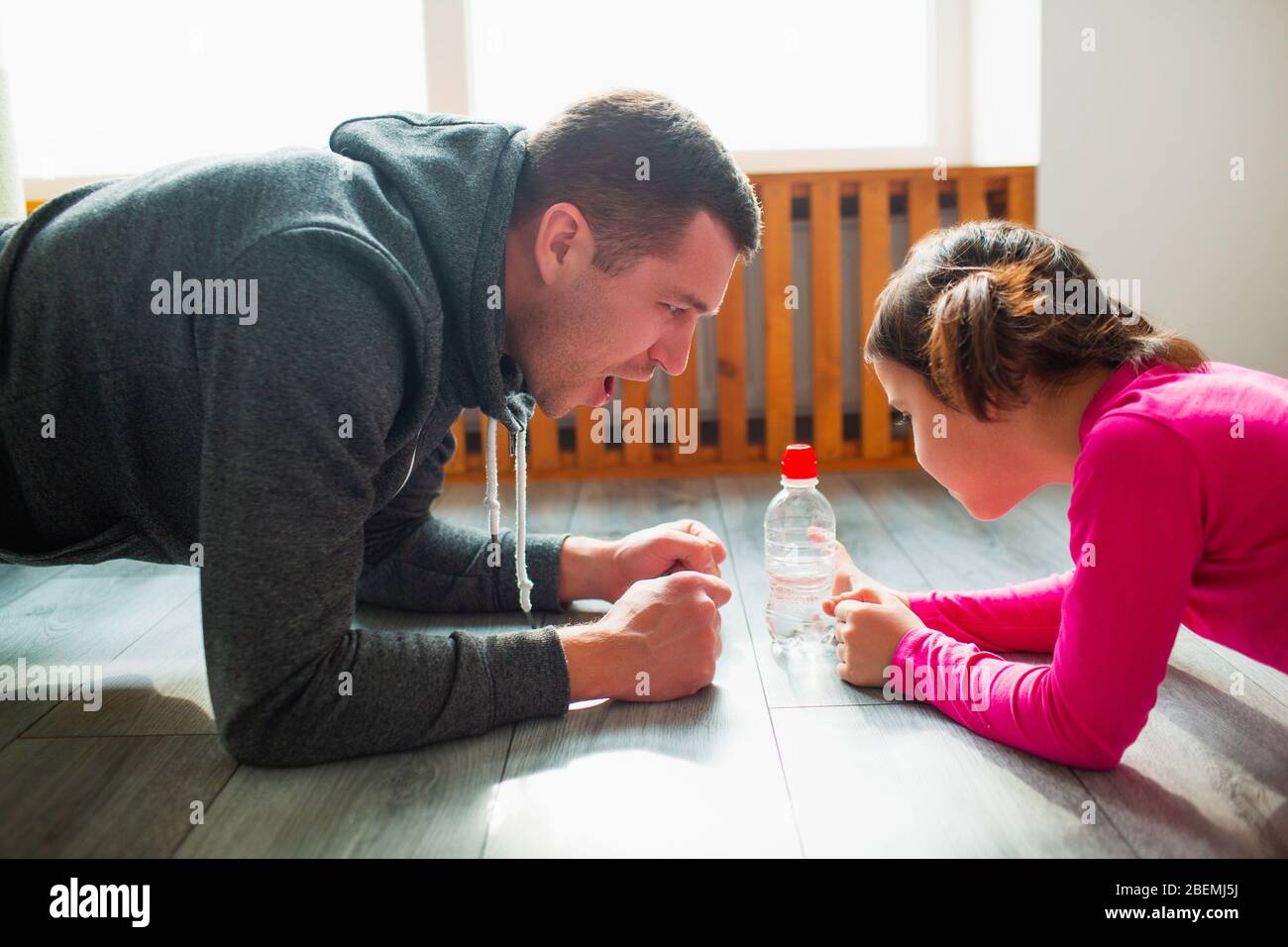 young-father-and-his-cute-little-daughter-are-doing-plank-on-the-floor