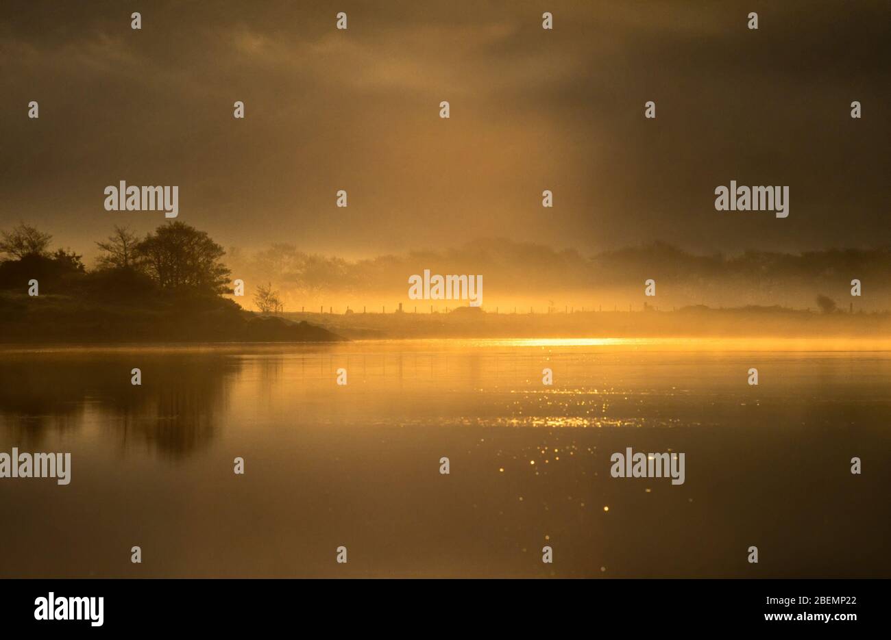 Misty orange sunrise over calm, misty waters of Loch Craignish, Ardfern, Lochgilphead, Argyll and Bute, Scotland, UK. Stock Photo