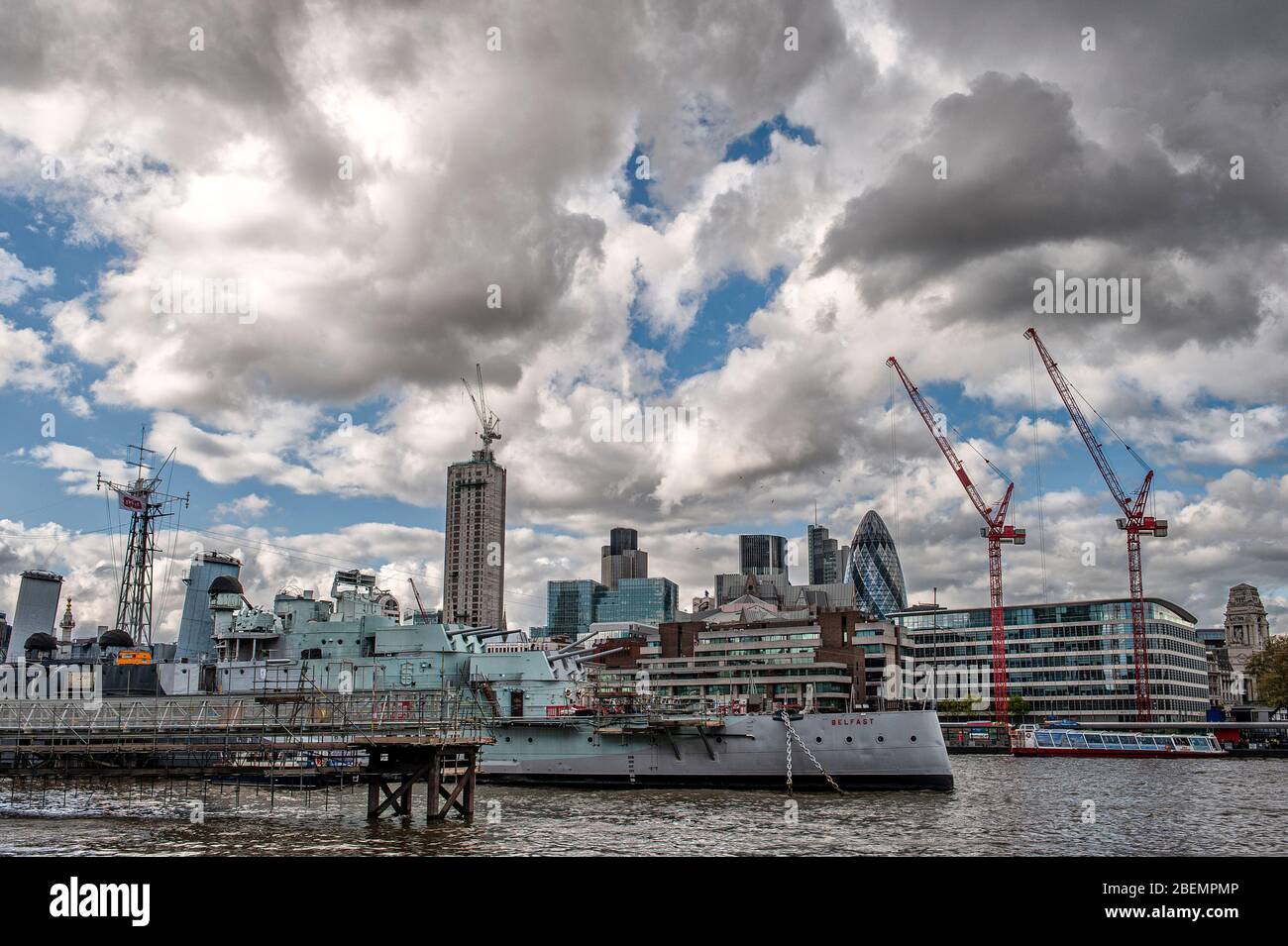 London, England. HMS Belfast: the museum ship on the River Thames. Used by the British Navy during the Second World War with the London skyline Stock Photo