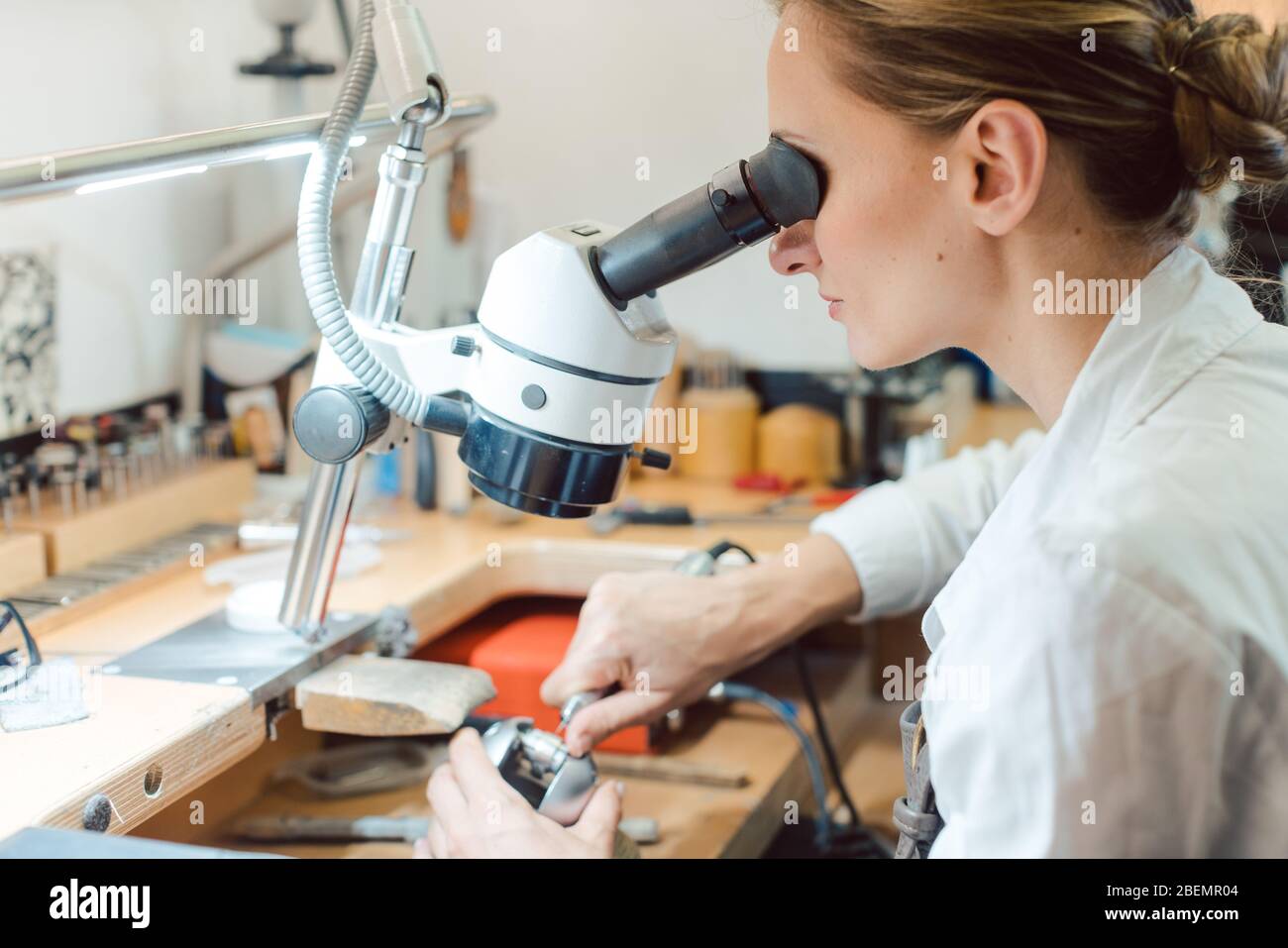 Diligent jeweler working on microscope at her workbench Stock Photo Alamy