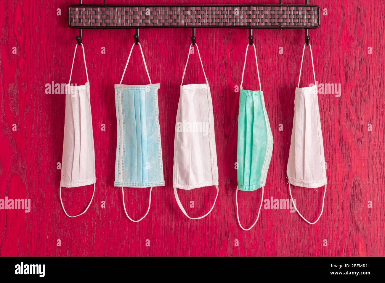 Medical masks hanging on hanger for family due to coronavirus protection covid-19 on red background Stock Photo