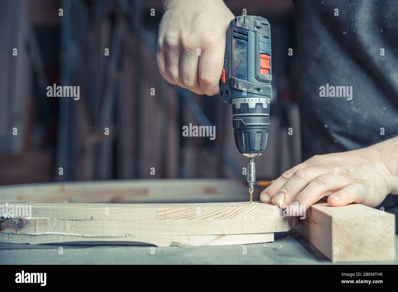 screwing wooden furniture in a joinery using an electric drill bit Stock Photo