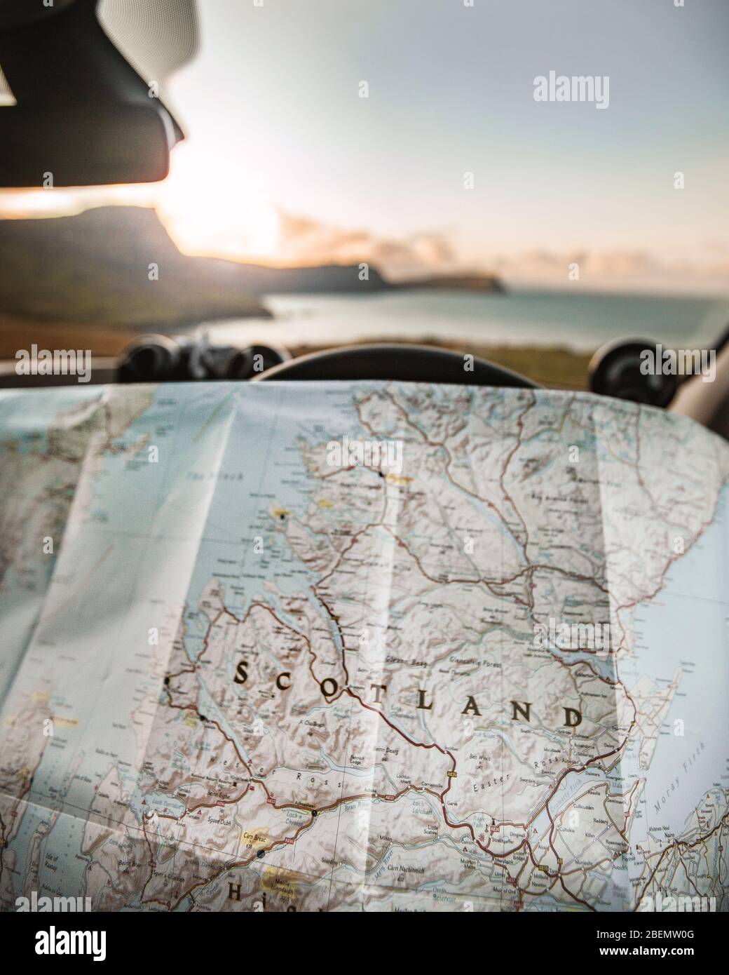 Planning a Road Trip adventure around Scotland with a map in hands parked overlooking the sunset Stock Photo
