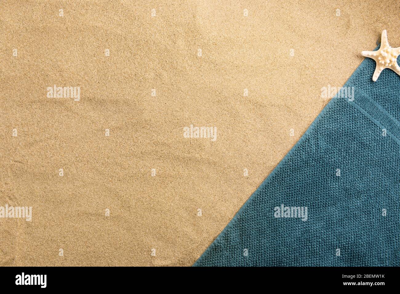 Summer vacation composition. Towel with seashell on sand background Stock Photo
