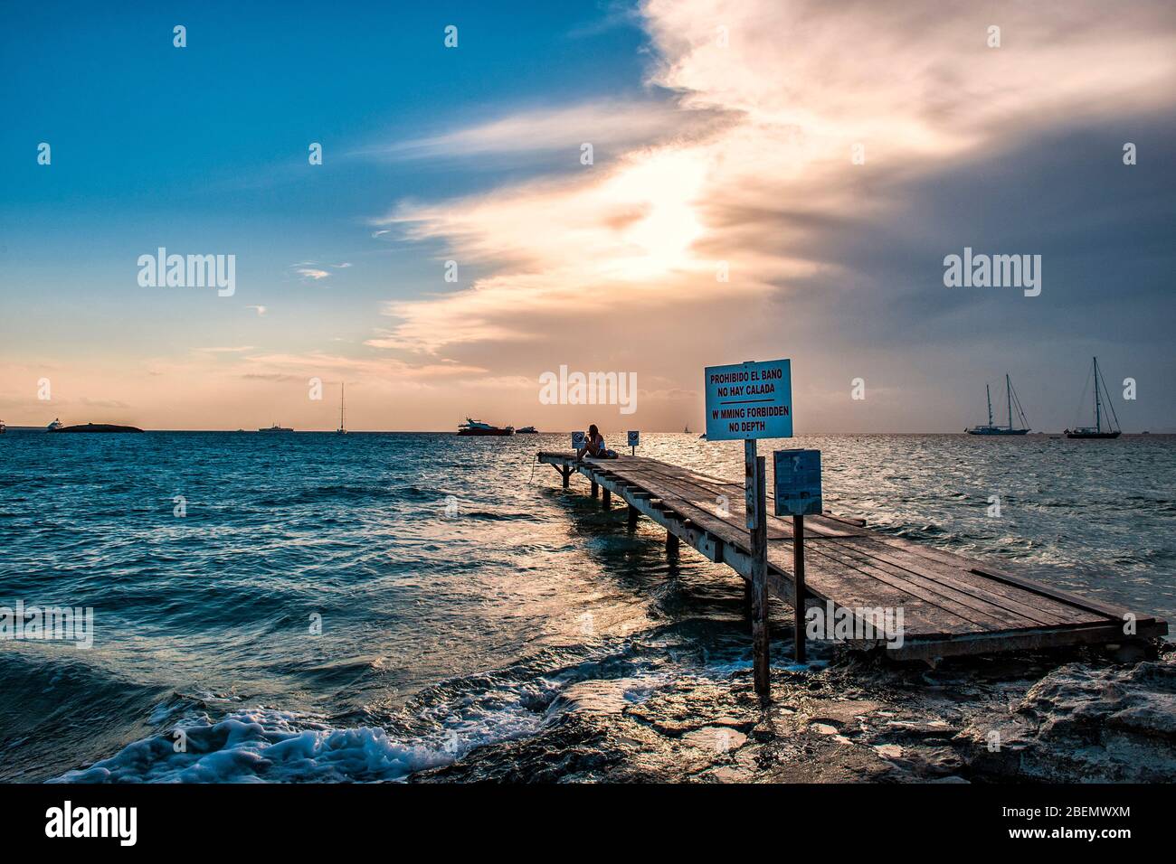 Ses Illetes Beach, Formentera, Balearic Islands, Spain. Photos at sunset of the sea walkway for mooring boats. A beautiful cloud covers the sun. Stock Photo