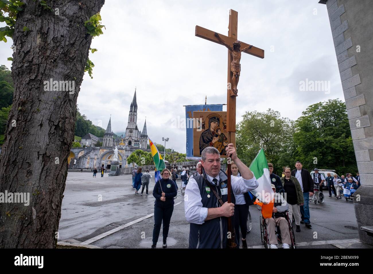 Eirish pilgrims carrying a cross with a sculptire of Jesus Christ walking on the grounds of the Lourdes sanctuary in Lourdes, France, Europe Stock Photo
