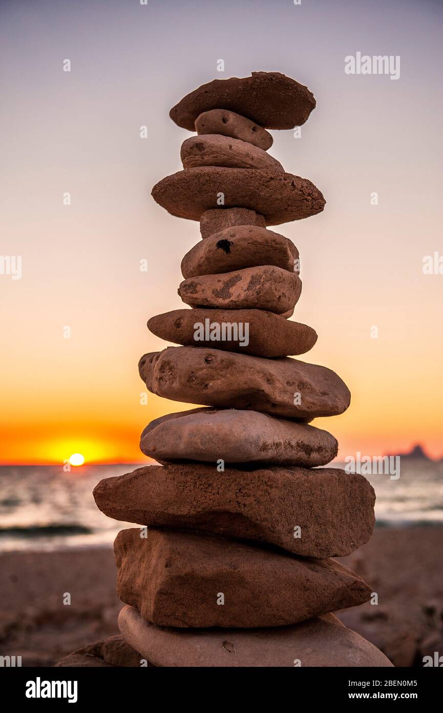 Ses Illetes Beach, Formentera, Balearic Islands, Spain, Massed stones at sunset that create a statue with the crystal clear sea in the background. Stock Photo
