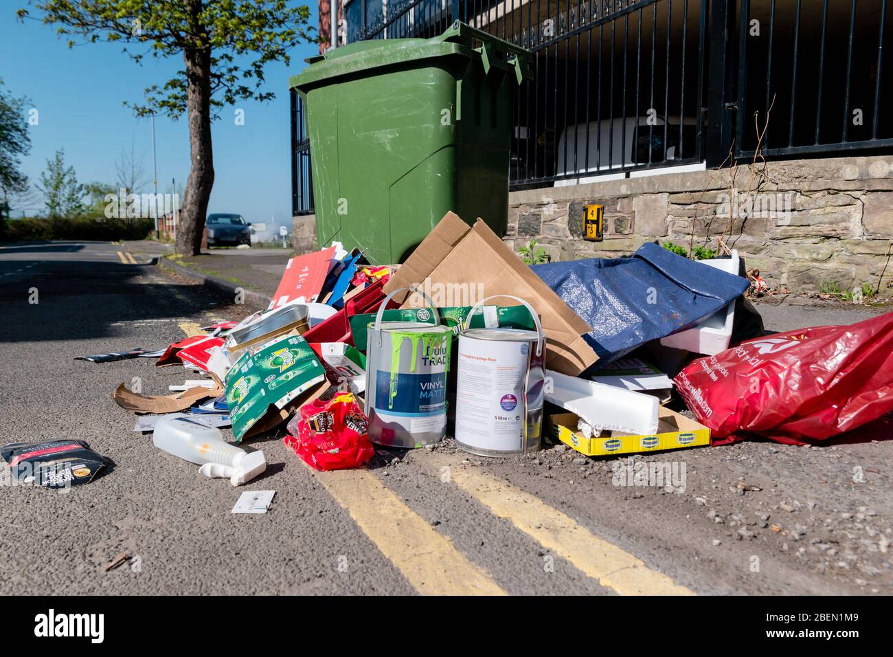Household type waste dumped on a public road near a wheelie bin