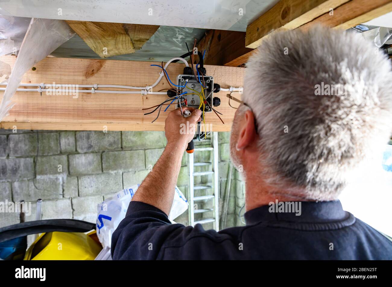 British welsh male wiring a junction box at home doing diy in garage Stock Photo