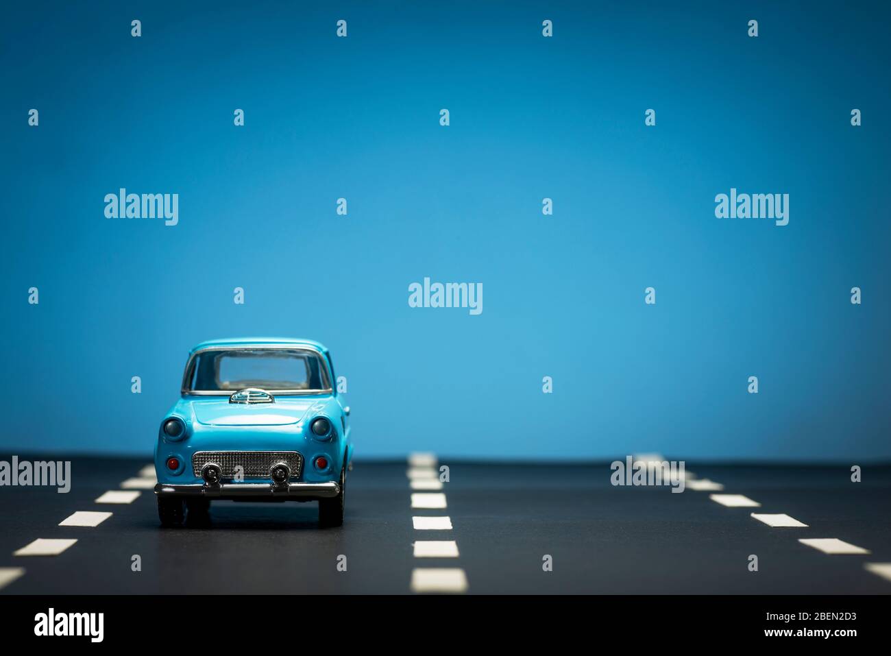 Front view of a blue toy car on on an asphalt road and a blue ...