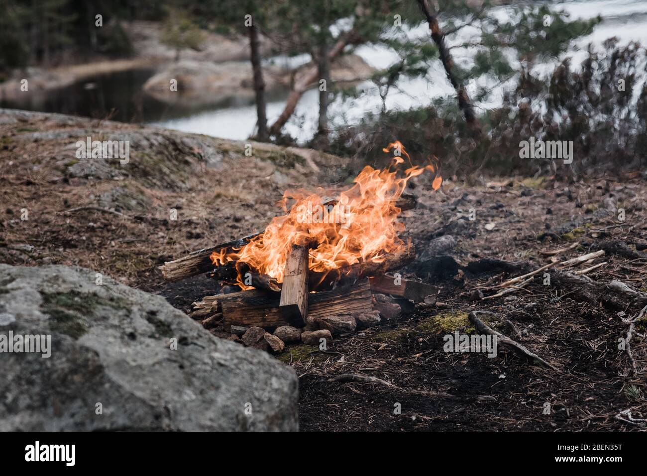 wild campfire next to the water in a national park in Sweden Stock Photo