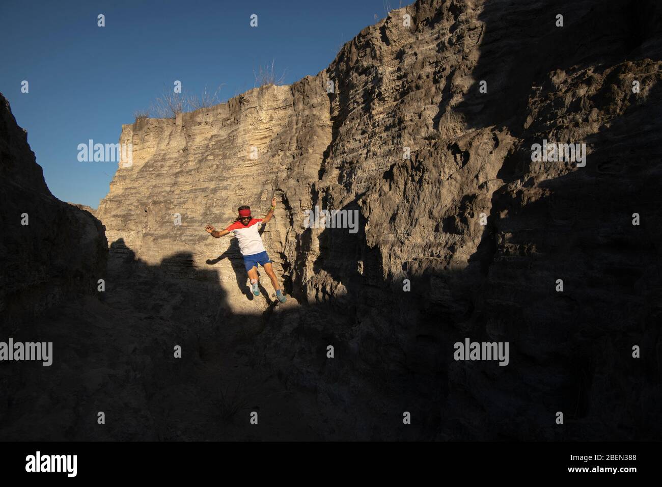 One man trail running on a small canyon with high contrast light Stock Photo