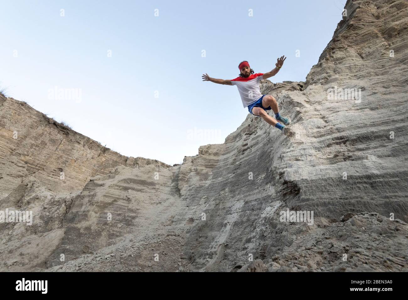 One man runs down on a very steep wall at an old mining waste of sand Stock Photo