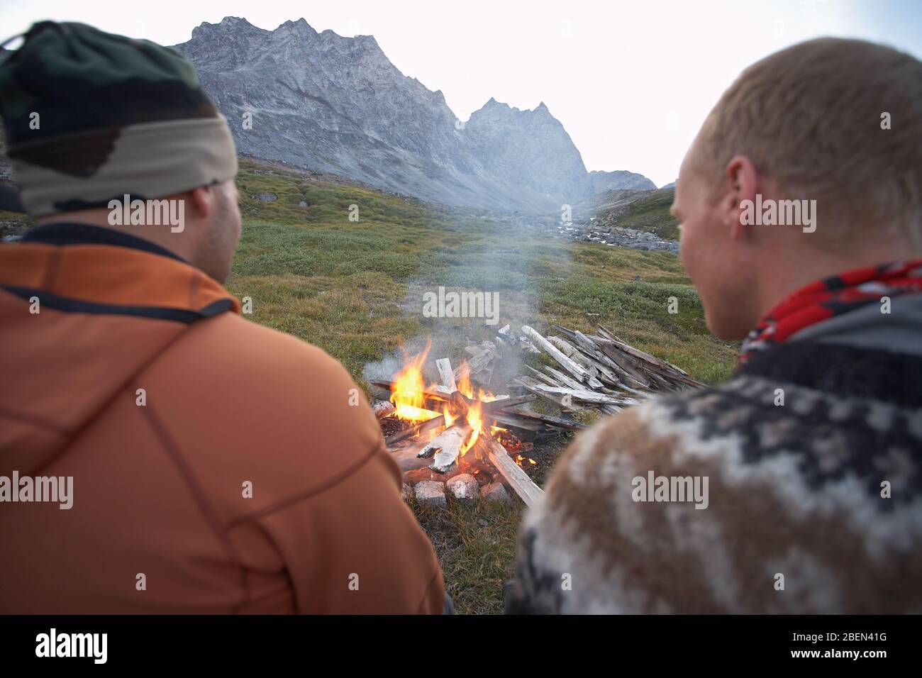 2 male friends sitting at a camp fire in Greenland Stock Photo