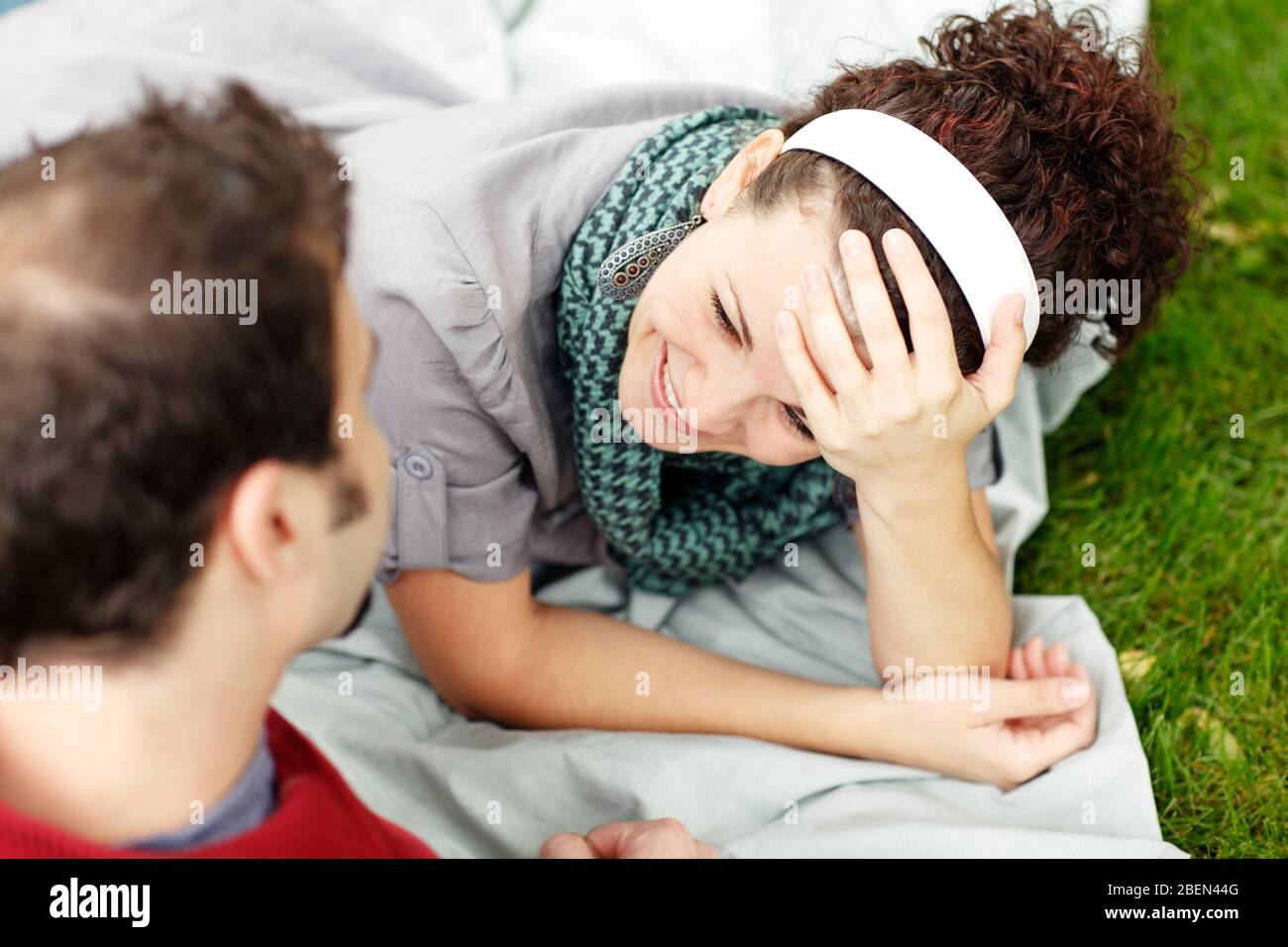 Woman smiling at her partner while laying on blanket in the gras Stock Photo