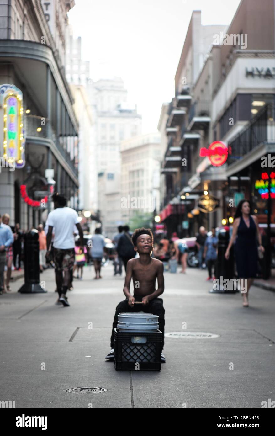 Young boy in New Orleans playing drums on a bucket on the street for tips. His older brother collected he’s cash while sitting on the corner just next Stock Photo
