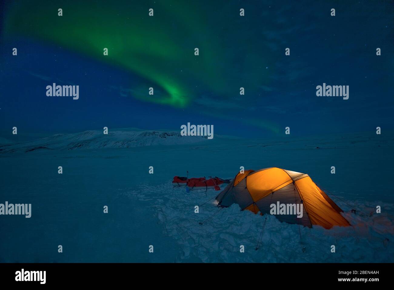 Aurora Borealis over an illuminated tent on Langjokull glacier Stock Photo