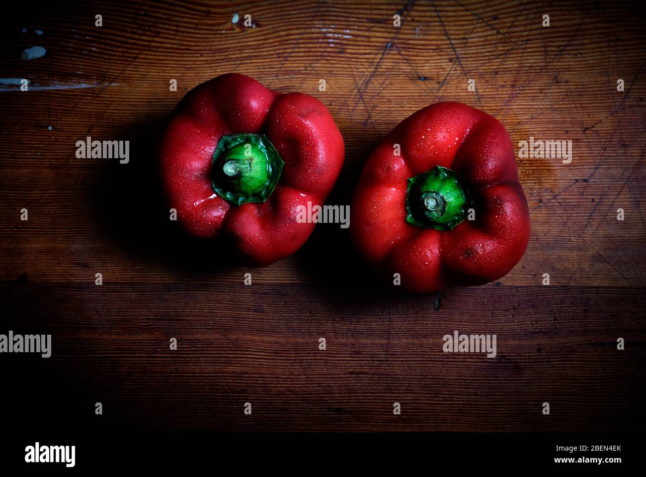 Two fresh red peppers with water drops on a wood table Stock Photo