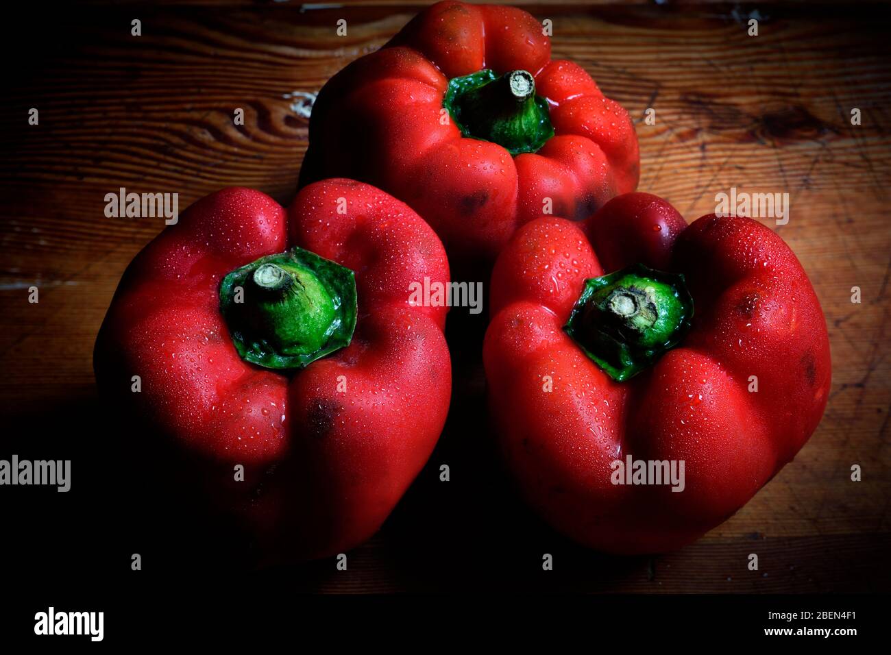Three peppers on a wood table Stock Photo - Alamy
