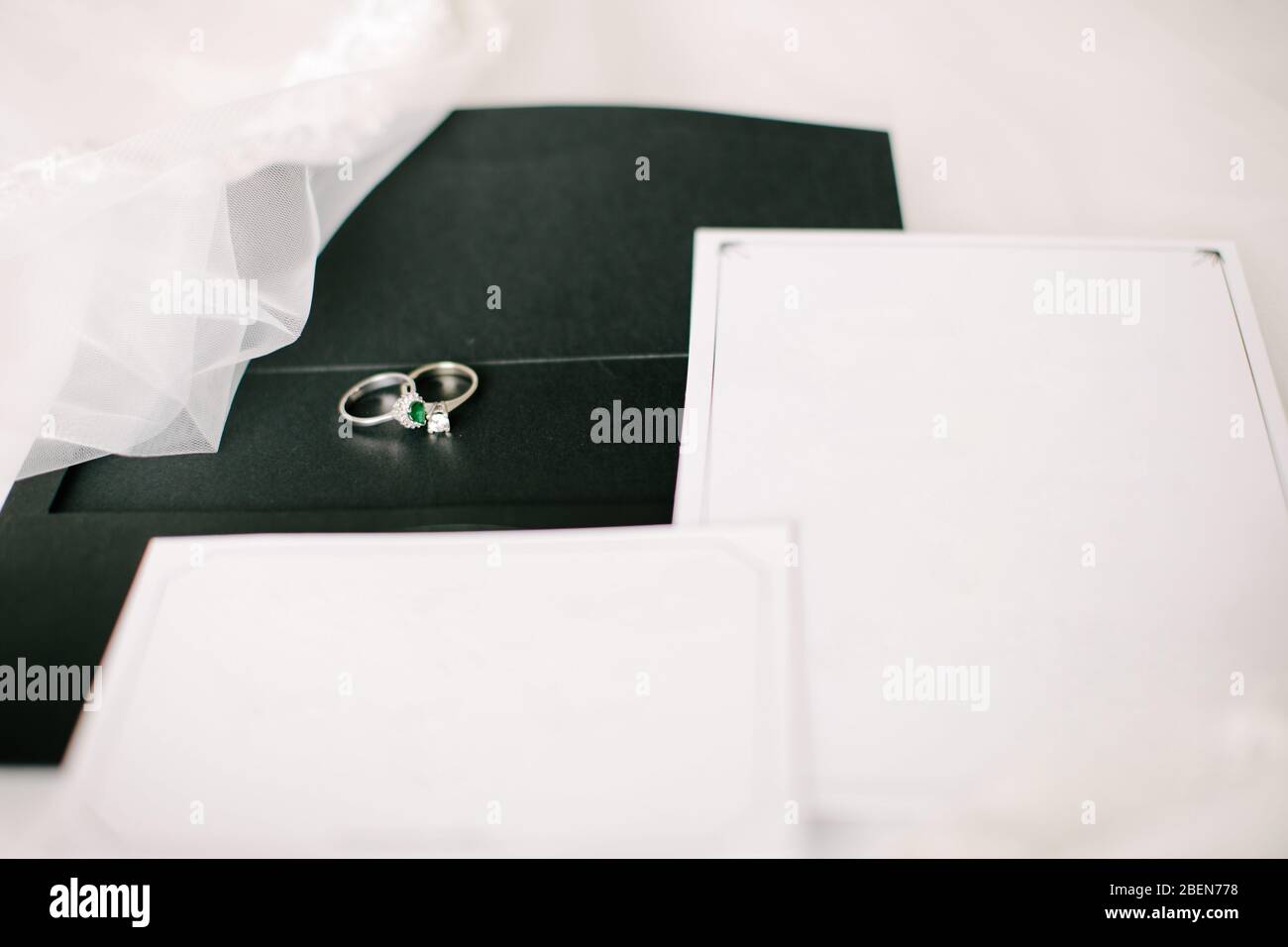 Wedding or engagement invitation. Empty white writing area. Wedding rings. Tulle on a floor. Stock Photo