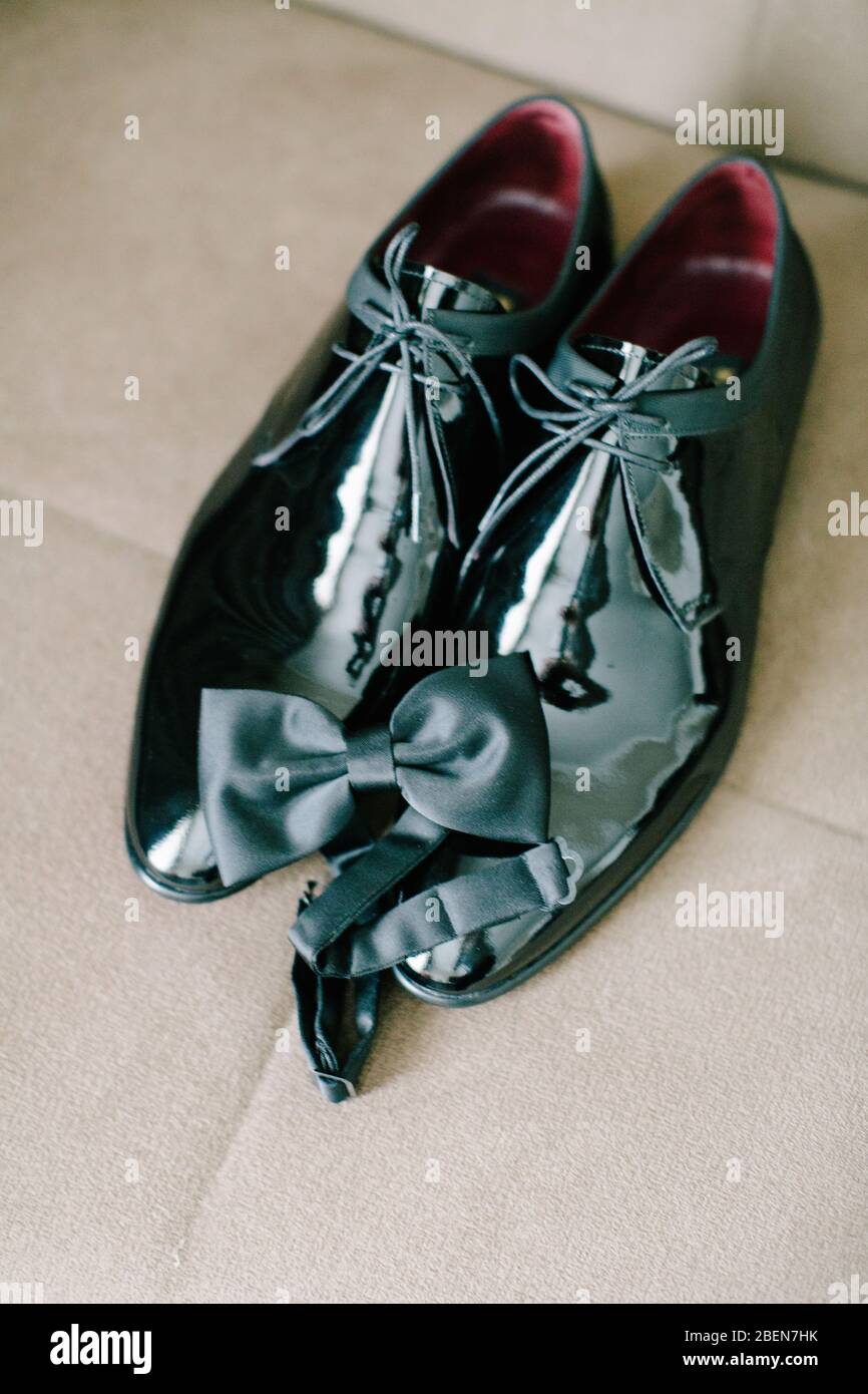 Black patent leather wedding shoes. Bow tie. Wedding reparations details. Indoor and close up. Stock Photo