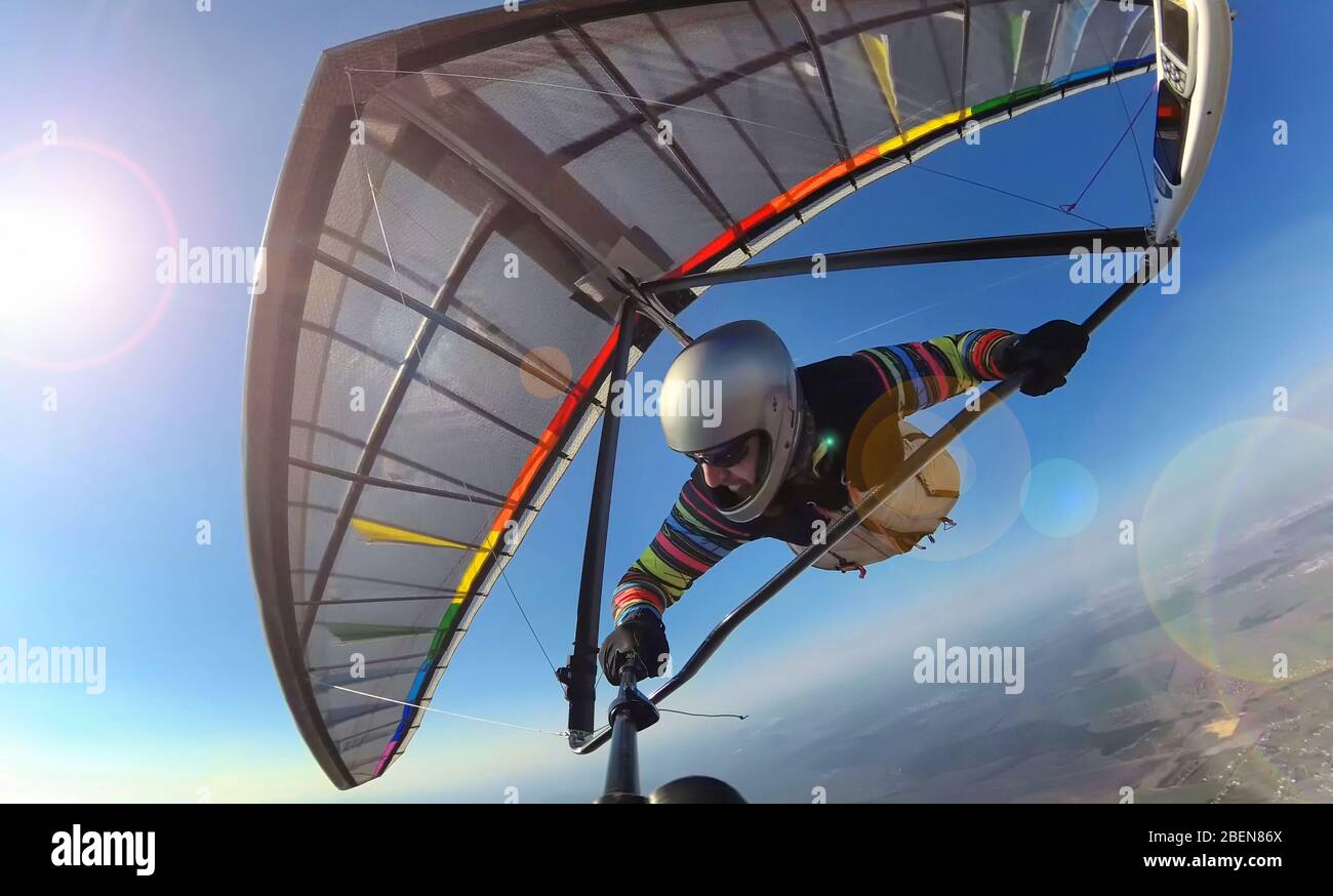 Hang glider pilot on colorful wing makes photo selfie high above ground. Concept of self isolation and social distancing activity. Extreme sport outdo Stock Photo