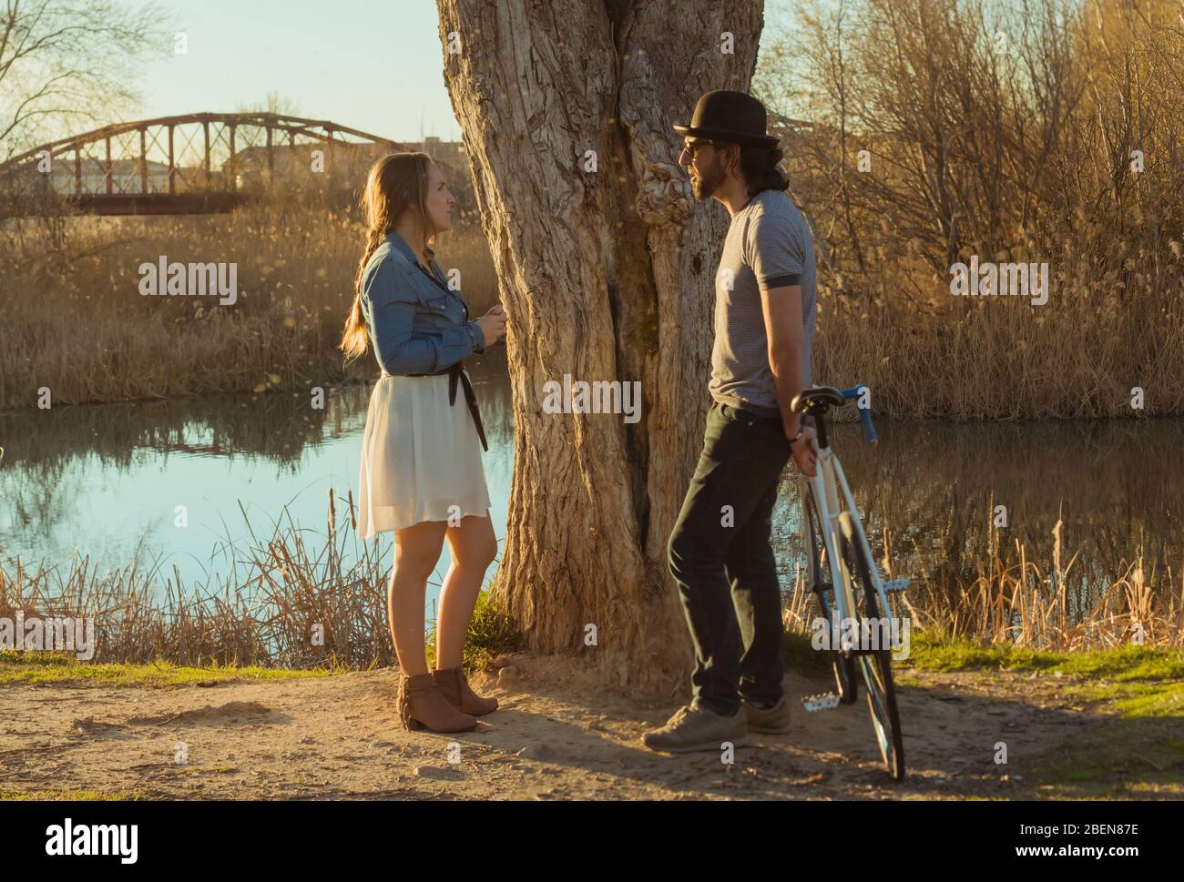 Couple in love talking in front of a river opposite each other Stock Photo