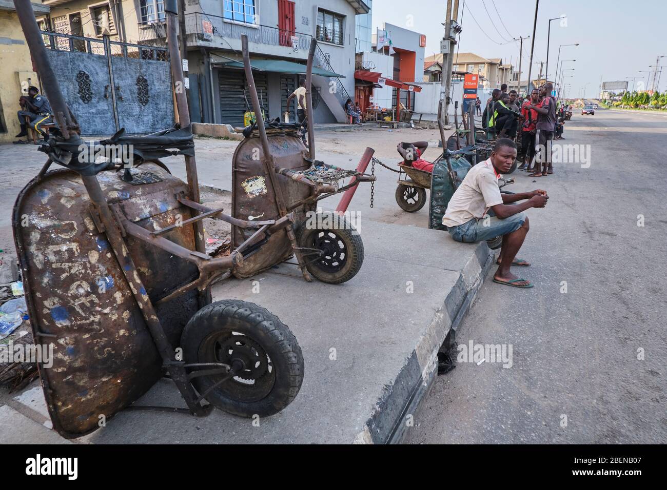 A wheelbarrow pusher sits as he waits for customers during the Covid-19 lockdown in Lagos, Nigeria. Stock Photo
