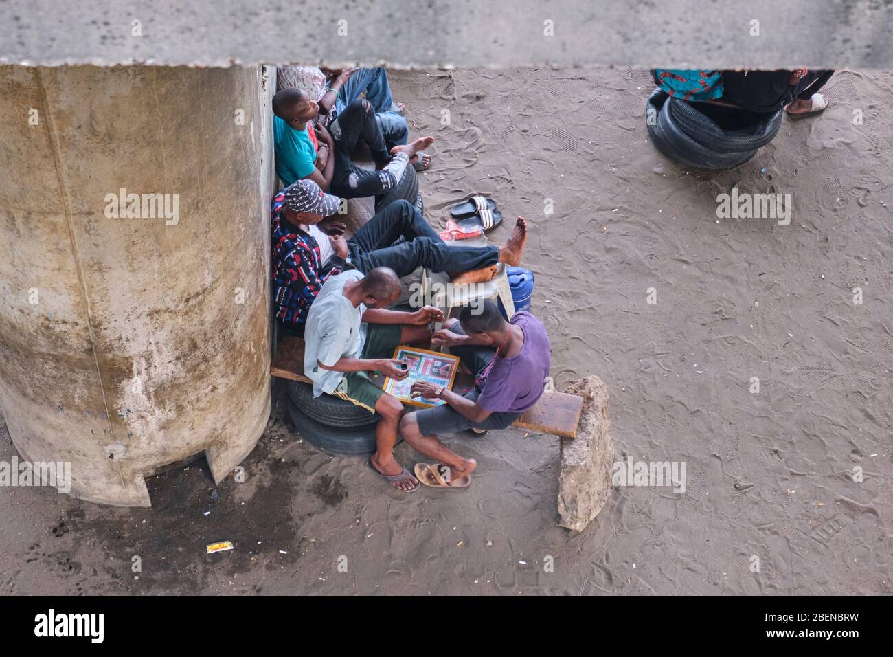 A group of boys hang out and play a game of Ludo under a bridge in Lagos, Nigeria. Stock Photo