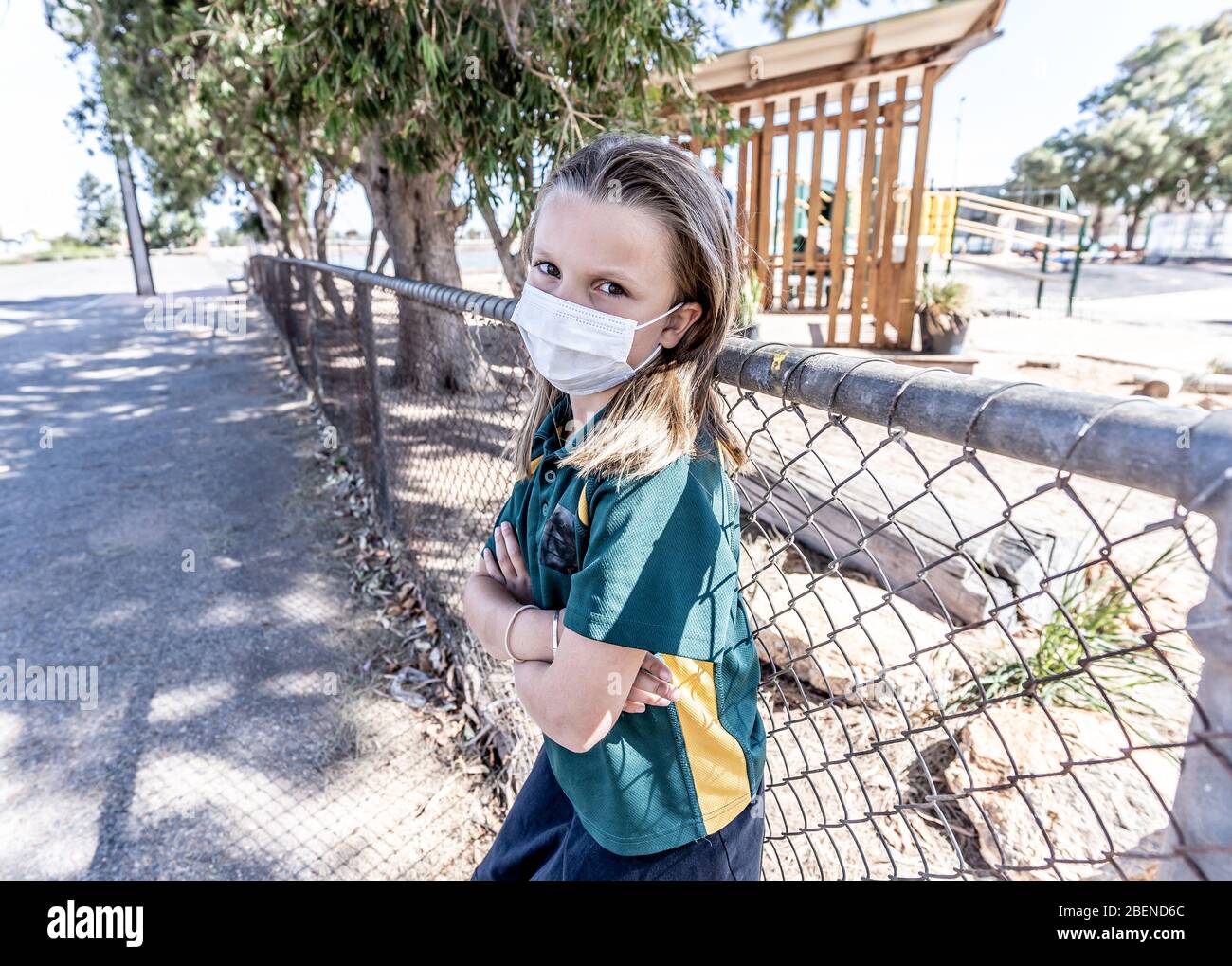 Covid-19 outbreak schools closures. Sad and bored Schoolgirl kid with face mask feeling depressed and lonely outside her closed school. Restrictions a Stock Photo