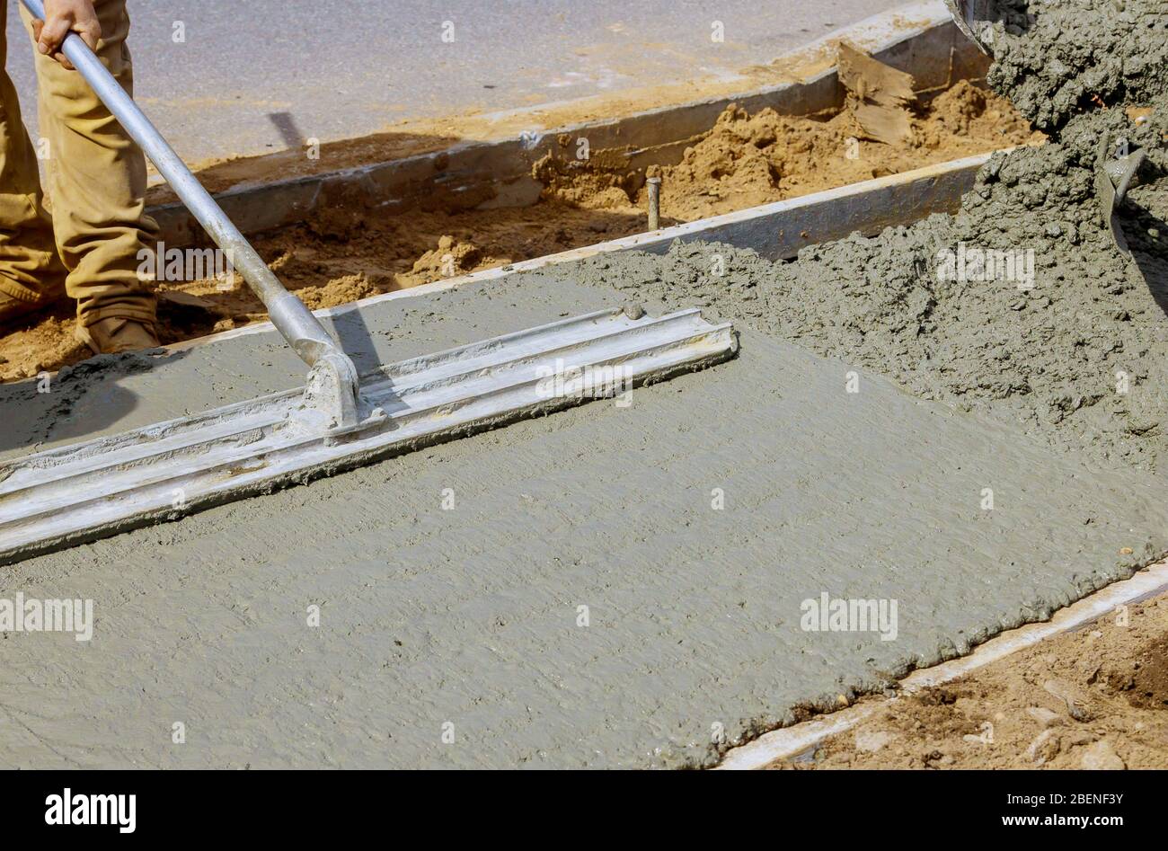 Construction filling formwork with cement and gravel worker pour cement for sidewalk in concrete
