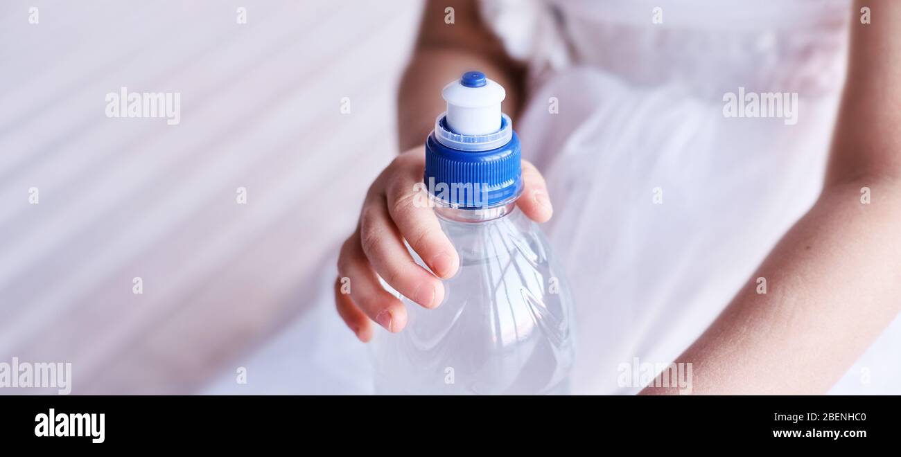 Young little girl hold water bottle. Kid drink cold fresh. Thirsty