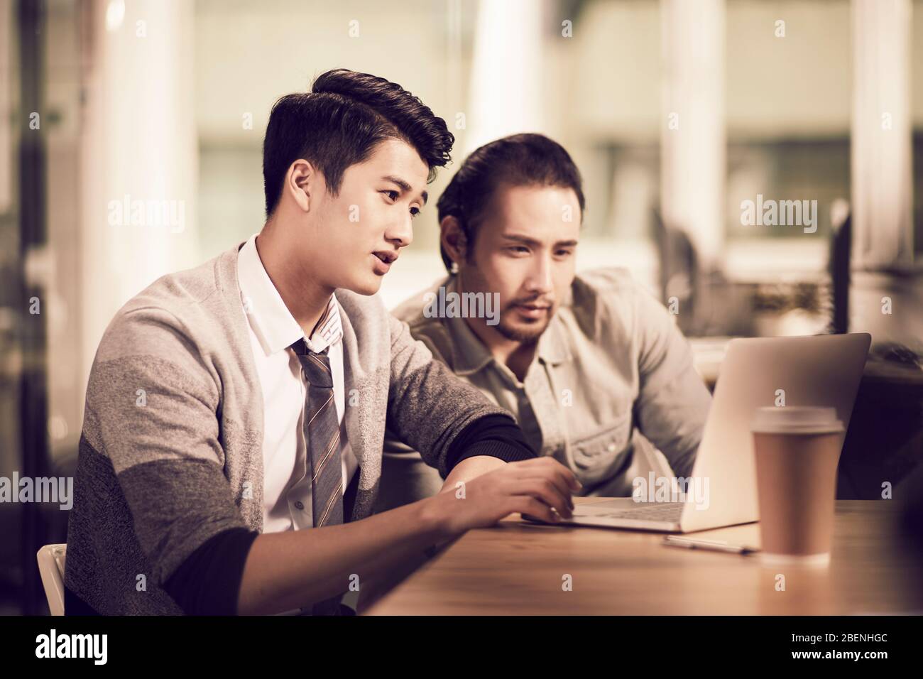 two young asian business men entrepreneurs working together in office using laptop computer Stock Photo