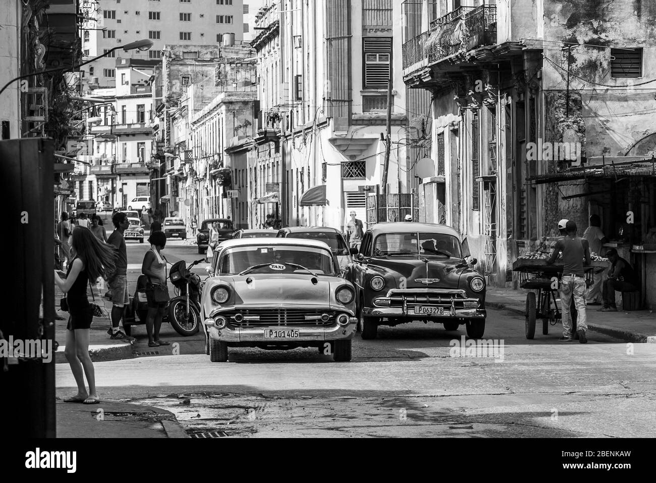 A pair of green classical cars in Centro Havana (Cuba) emerge from the shadows cast by the rising sun as they had towards the old town area in Novembe Stock Photo