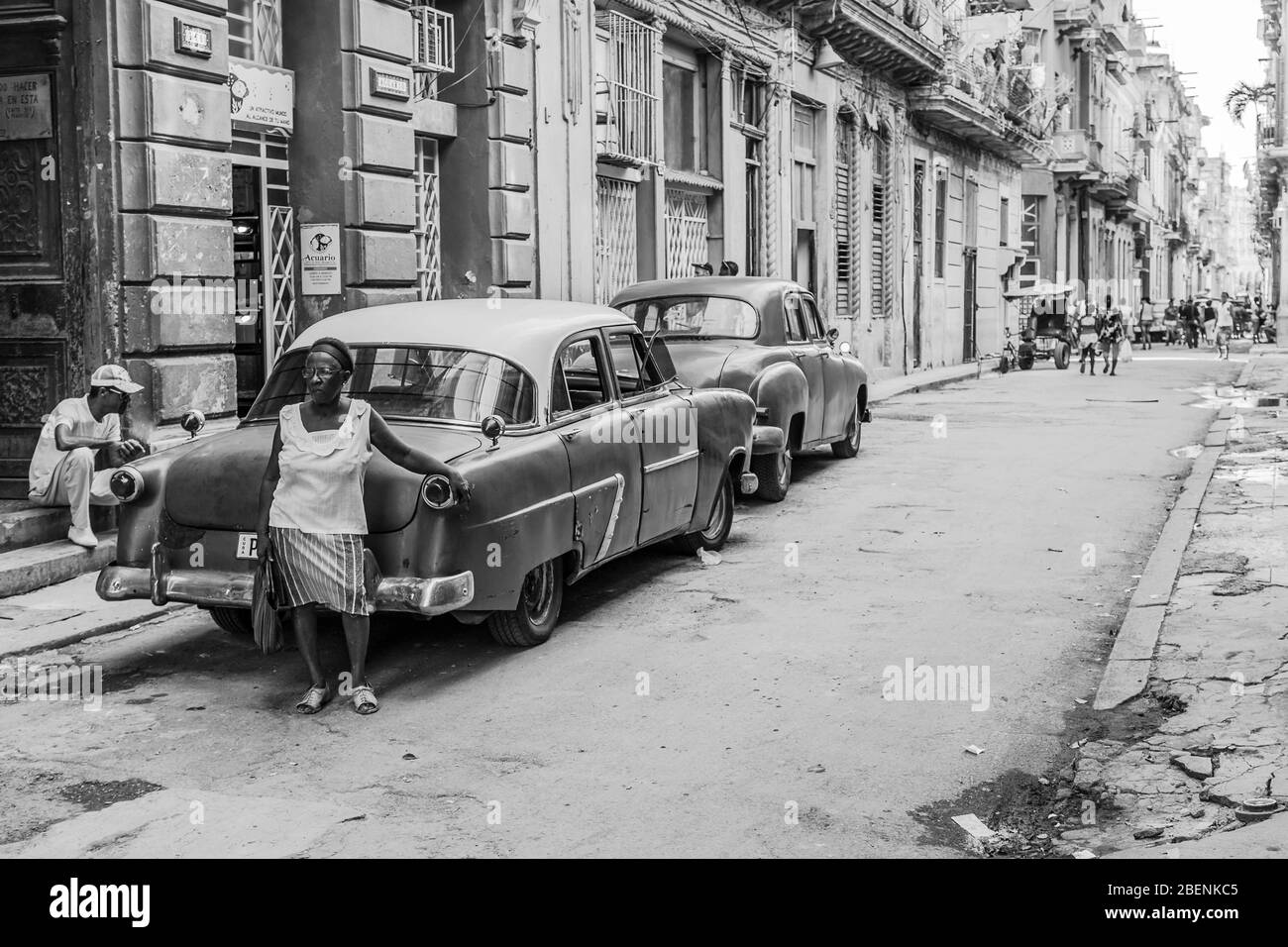 A Havanan woman rests against a car as she waits for oncoming traffic to pass her by in Havana, the capital city of Cuba in August 2014. Stock Photo