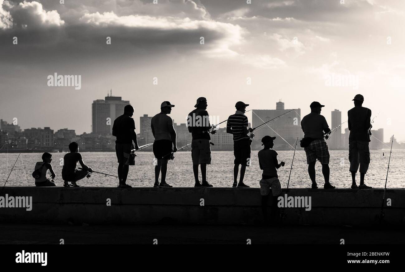 A row of local men stood next to one another fishing off the ocean wall off the Malecon highway in Havana, Cuaba during August 2014. Stock Photo