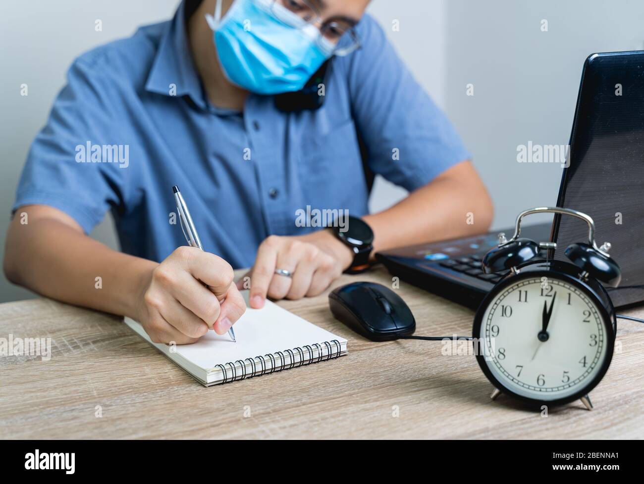 Work from home during the outbreak of the virus. At midnight, the businessman was working from home, he was talking on the phone and taking notes of Stock Photo